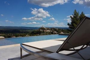 a chair sitting on a patio next to a swimming pool at Villa Font Garenne in Crillon-le-Brave