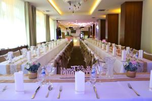 una lunga sala banchetti con tavoli e sedie bianchi di Hotel Rezident a Turčianske Teplice