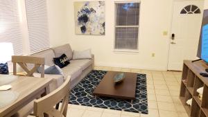 uma sala de estar com um sofá e uma mesa em Modern House Minutes from Downtown Gainesville, UF, VA & More! em Gainesville
