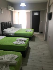 three beds in a room with green sheets at Anatolia Hotel in Pamukkale