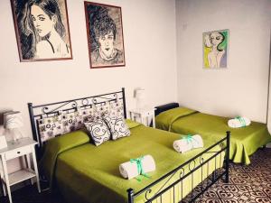 two beds in a bedroom with green sheets at Casa Elide in Catania