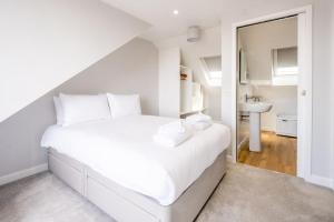 a white bedroom with a white bed and a sink at Elm Cottage in Aldeburgh