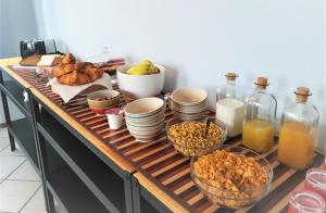 a wooden counter with bowls of food and bottles of orange juice at 1928 Guest House in Pogno