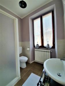 een badkamer met een wastafel, een toilet en een raam bij 1928 Guest House in Pogno