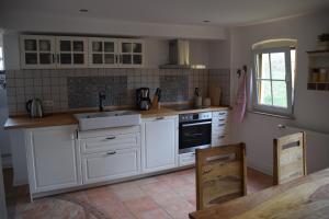 a kitchen with white cabinets and a sink at Ferienwohnung Tauberzell in Adelshofen