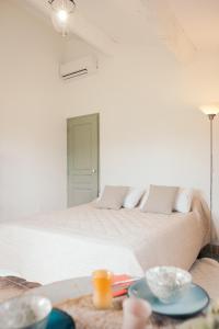 a white bedroom with a bed and a table at Le jardin du Castillon in Paradou