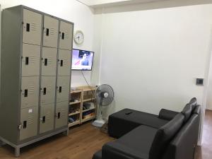 a living room with a couch and a tv and lockers at Anna Hostel in Chaiyaphum in Ban Sieo