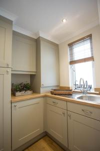a kitchen with white cabinets and a sink and a window at Hollicarrs - Forest Retreat in York