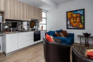sala de estar con sofá azul y cocina en 901 - The Sentinel, en Ciudad del Cabo