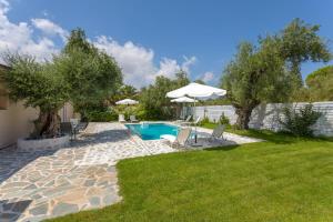 um quintal com uma piscina e um guarda-sol em Michaelo Villa - Affordable Luxury! em Kalamaki
