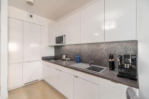 a kitchen with white cabinets and a sink at Family Holiday Apartment Aquamarina Prima by Renters in Międzyzdroje