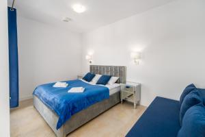 1 dormitorio con cama con sábanas azules y sofá en Family Holiday Apartment Aquamarina Prima by Renters, en Międzyzdroje