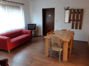 a living room with a table and a red couch at Prenociste Pecinci Biker Friendly in Pećinci