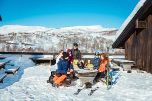 Eine Gruppe von Menschen, die an einem Tisch im Schnee sitzen in der Unterkunft Haukelifjell Skisenter in Vågsli