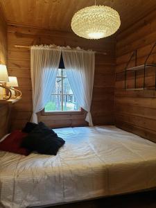 a bedroom with a bed with a window and a chandelier at PyhäBerry in Pelkosenniemi