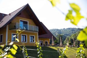 a yellow house with a balcony on the side of it at Weingut-Gästezimmer UHL in Ratsch an der Weinstraße