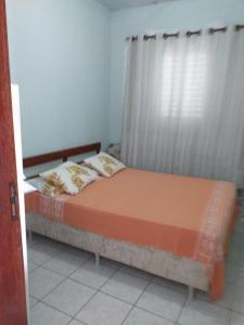 a bed sitting in a room with a window at Residencial Gil in Palhoça