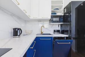 a kitchen with blue cabinets and a black refrigerator at Apartament przy Bulwarach Wiślanych Kościuszki by Renters in Krakow