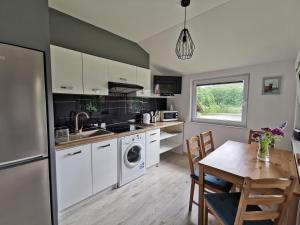 a kitchen with white cabinets and a table and a dining room at Domek u Cioci Meli in Brodnica Dolna