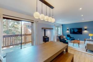 a dining room with a table and a living room with a balcony at Mammoth Ski & Racquet 93K in Mammoth Lakes