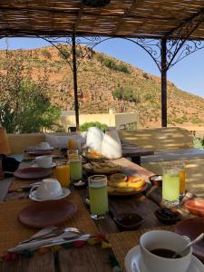 una mesa de madera cubierta con platos de comida y bebida en Dar El Mandar - Ferme & Table d'Hôte Berbère, en Bhalil
