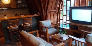 una sala de estar con TV y sillas y un bar en Villa Lumbung Amertha Sari, en Lovina