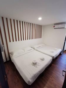 two beds in a room with white sheets at Kuching Hotel in Kuching