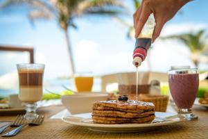 a person drizzling syrup onto a piece of food on a table at Las Villas Akumal in Akumal