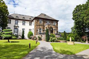 a large stone house with a grass yard at Schloss Hotel Burgbrohl in Burgbrohl
