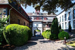 a courtyard of a house with trees and bushes at Schloss Hotel Burgbrohl in Burgbrohl