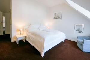 a white bedroom with a white bed and a blue chair at Schloss Hotel Burgbrohl in Burgbrohl