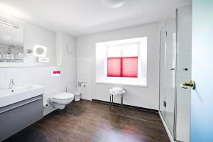 a white bathroom with a toilet and a window at Schloss Hotel Burgbrohl in Burgbrohl