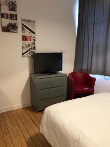 1 dormitorio con 1 cama, TV y silla en Som-home, en Péronne