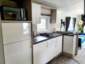 una pequeña cocina con fregadero y microondas en Foxwood Lodge Private Hot Tub Getaway, en Swarland