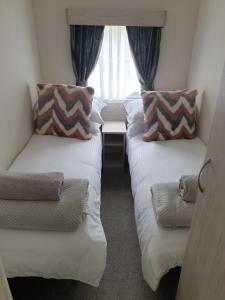 two beds in a small room with a window at Foxwood Lodge Private Hot Tub Getaway in Swarland