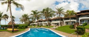 an exterior view of a resort with a swimming pool and palm trees at Las Villas Akumal in Akumal