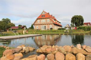 ein großes Haus mit einem Teich davor in der Unterkunft Landhaus Fünfseen in Funfseen