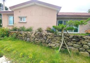 a stone retaining wall in front of a house at Fongnang Eyeom in Jeju