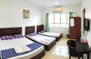 a room with two beds and a table and a desk at Hotel Tanjong in Tanjung Malim