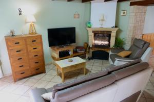 uma sala de estar com um sofá e uma televisão em AU COEUR DU MARAIS em Saint-Hilaire-la-Palud