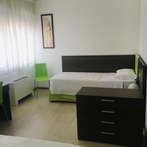 a bedroom with a bed and a desk and a green chair at Hotel Affittacamere alla Posta in San Giórgio di Nogaro