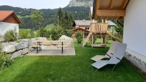 een patio met een tafel en stoelen in een tuin bij Alpenappartement Kleiner in Tannheim