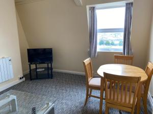 uma sala de jantar com uma mesa e uma televisão em Serviced Property Apartment em Plymouth