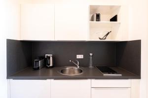 eine Küche mit einem Waschbecken und weißen Schränken in der Unterkunft Das Loft Apartments in Aachen