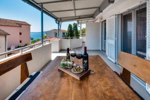 una mesa de madera con botellas de vino y comida en el balcón en Take A Break Apartments, en Brodarica