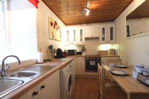 a kitchen with white cabinets and a wooden ceiling at The Wee Nook Birnam in Birnam