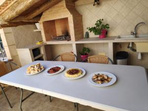una mesa blanca con cuatro platos de comida. en Casa Rural Ladrón de Semillas, en Elche de la Sierra
