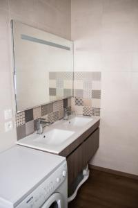 bagno con 2 lavandini, specchio e lavatrice di Logement cosy 4/6 pers - quartier historique calme a Cauterets
