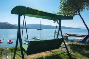 a swing bed on the shore of a lake at Flisvos Seaside Apartments in Lygia
