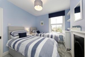 deux lits dans une chambre aux murs bleus et une cheminée dans l'établissement Pepperpot Cottage, à Whitstable
